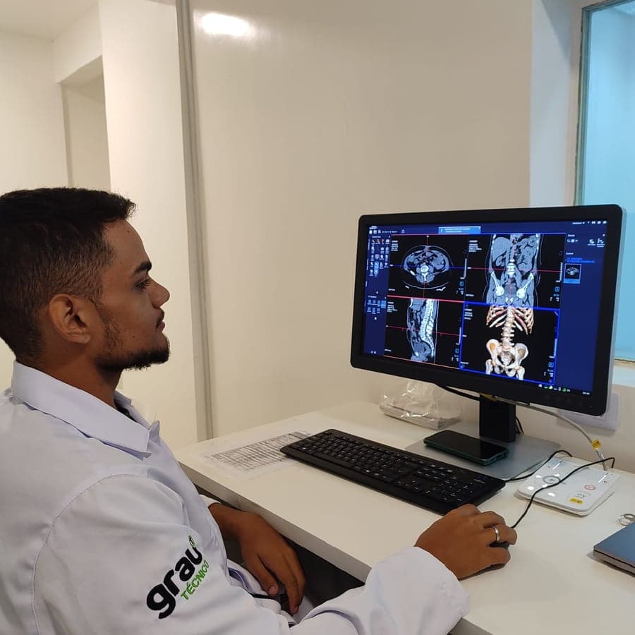 Técnico operando o workstation de tomografia computadorizada
